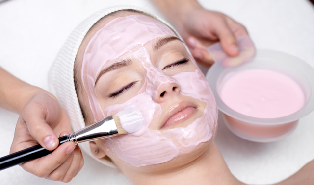 Girl receiving cosmetic pink facial mask